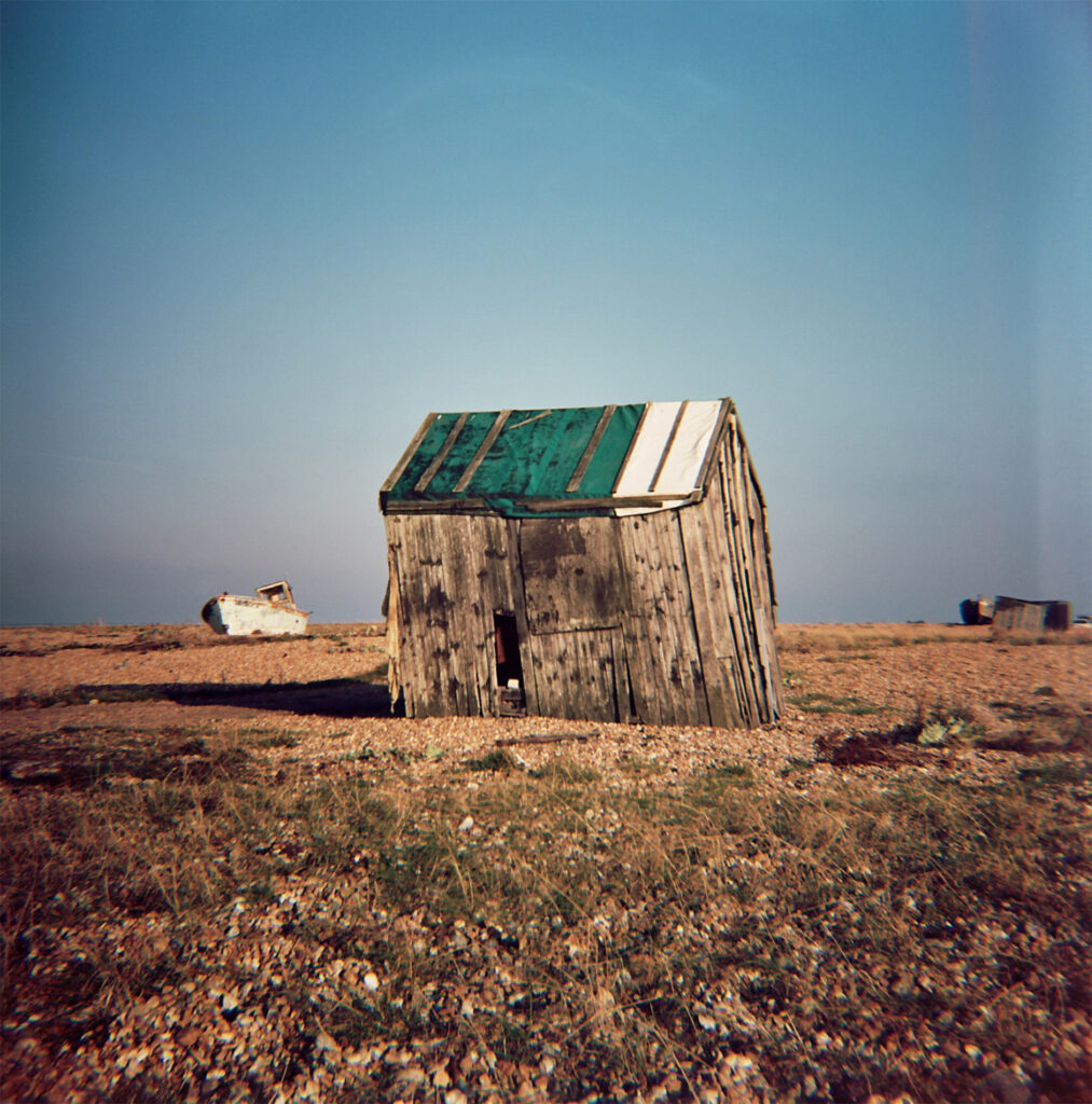 The current image has no alternative text. The file name is: ARTSPhotoHastings-Frank-Francis-A-green-roofed-hut-at-Dungeness-clings-to-the-shingle-as-it-remains-defiant-until-the-end.jpg